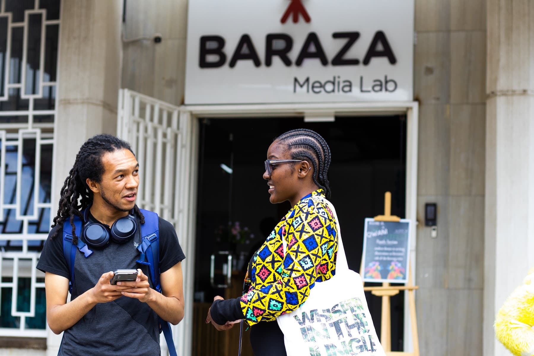 Two festival-goers talking outside the Baraza Media Lab entrance