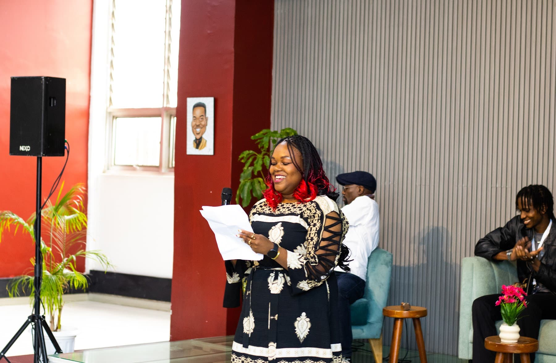 A woman reading aloud from a sheet of paper on stage