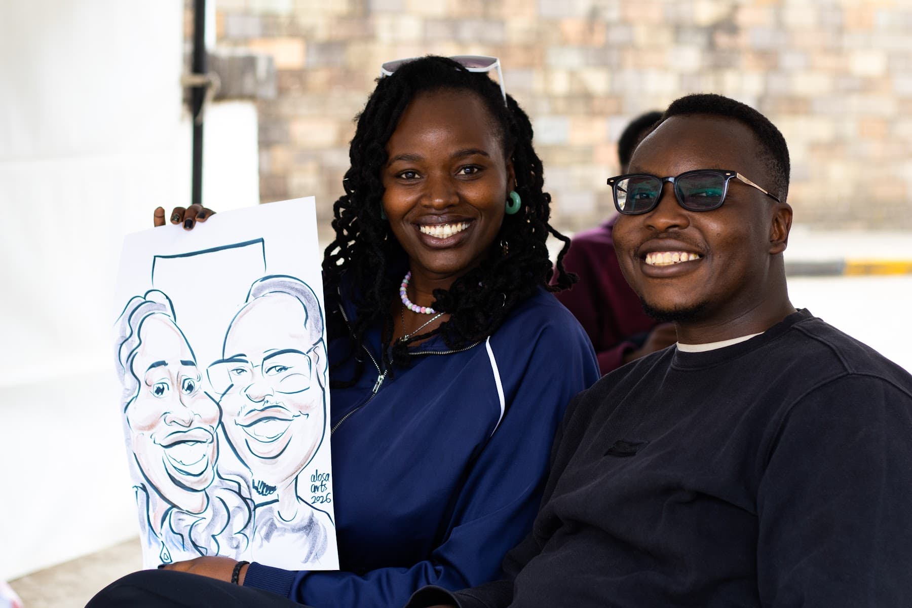 A smiling couple holding up the caricature just drawn of them