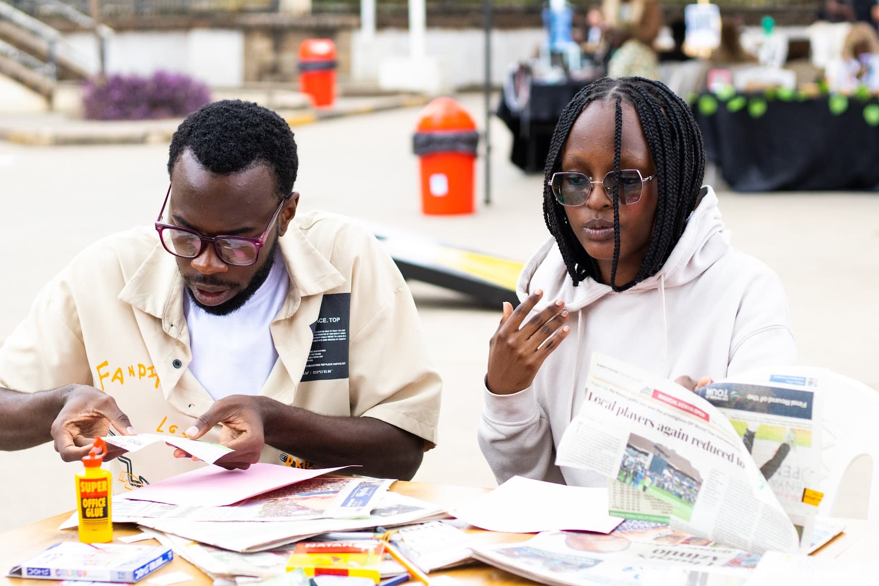 Two attendees cutting paper at the zine-making table